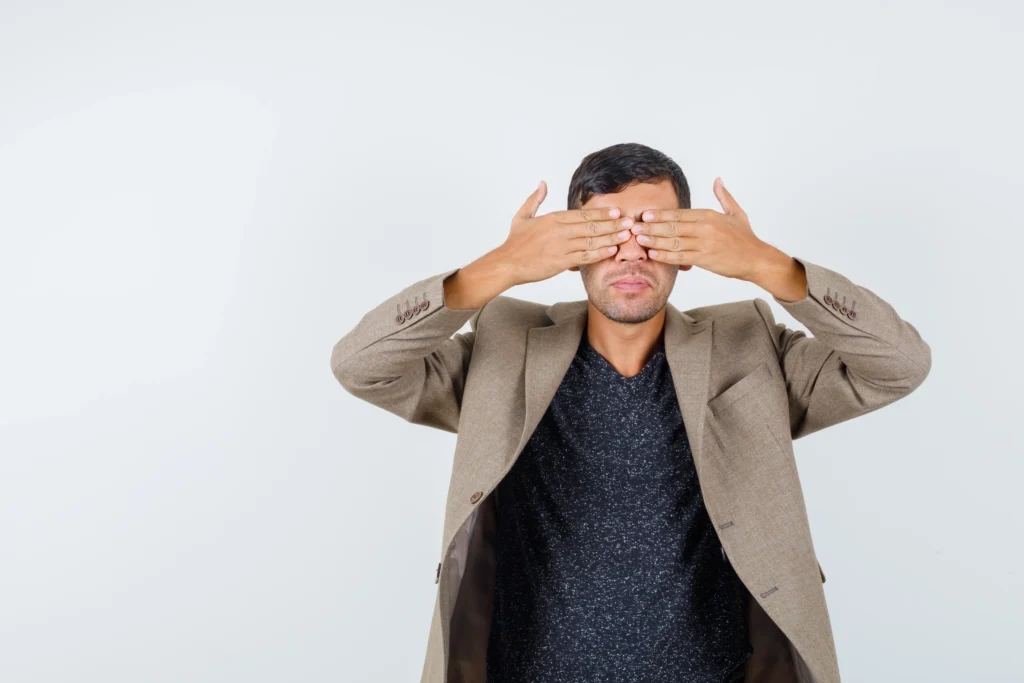 young male grayish brown jacket black shirt closing his eyes with hands looking shy front view