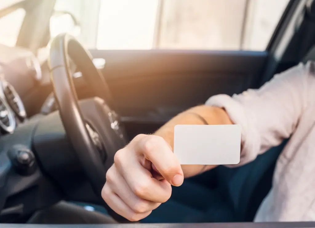 man showing business card car